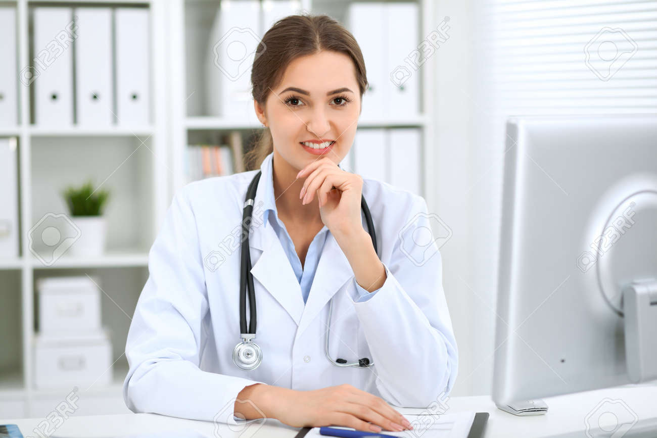 80119589-latin-american-female-doctor-sitting-at-the-table-and-working-by-computer-at-hospital-office-the-1